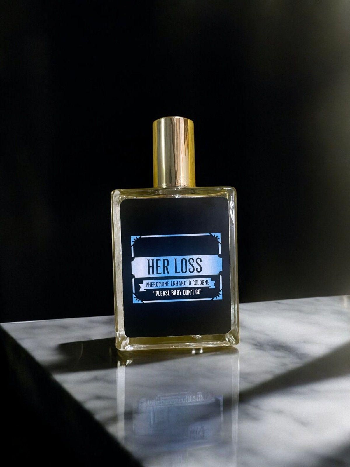 Her Loss signature perfume displayed on a marble surface, featuring a gold cap and sleek design.