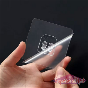 Transparent self adhesive wall hooks being peeled from packaging for easy installation