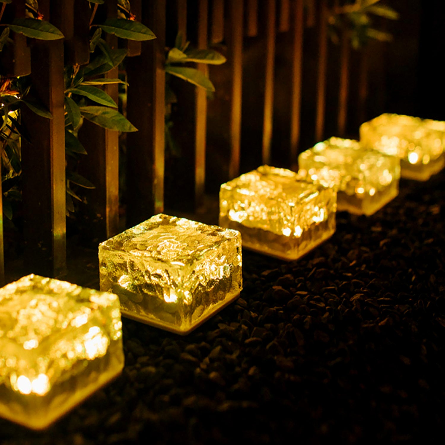 Ice cube shaped outdoor lights shining warmly in a garden pathway at night