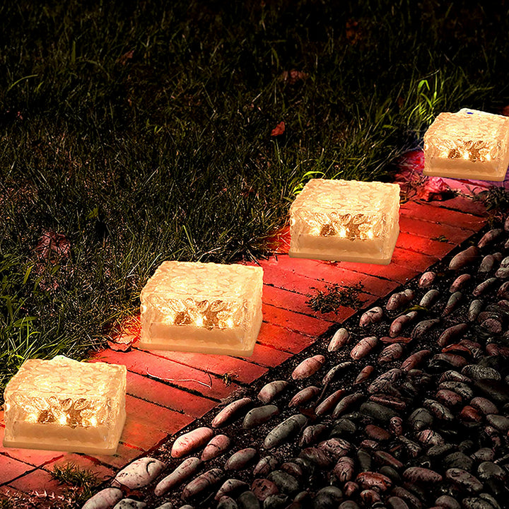 Ice cube shaped outdoor lights illuminating a garden pathway with a warm glow
