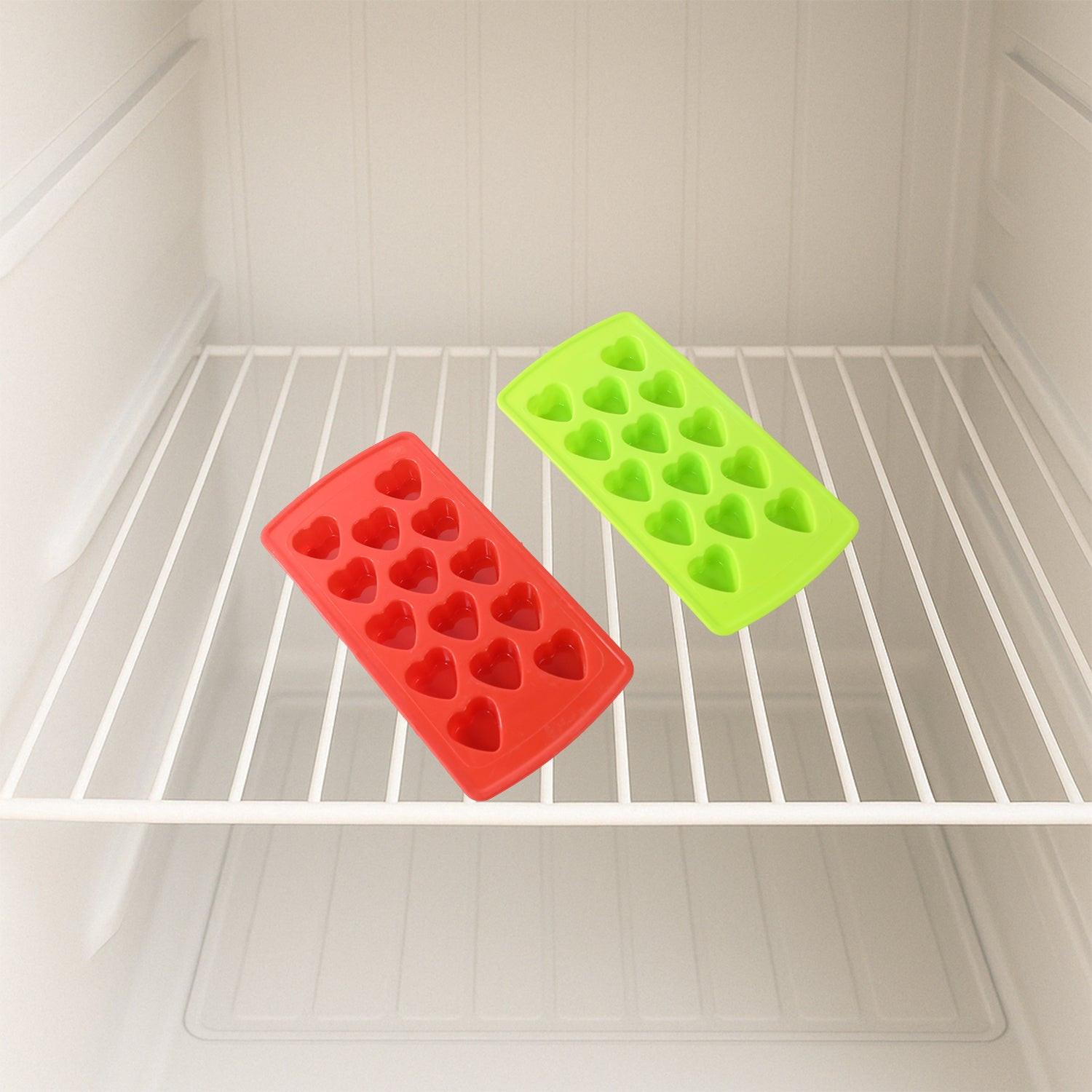 Colorful ice cube tray set in red and green heart shapes placed in a freezer