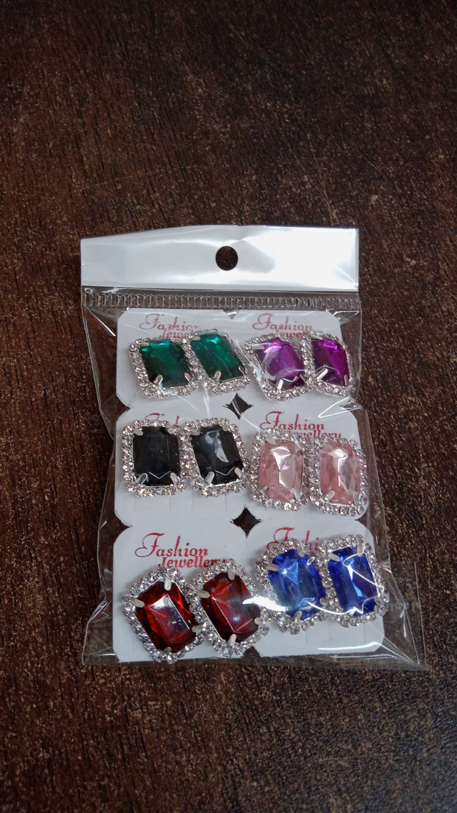 Set of interchangeable diamond earrings in various colors including red, green, and purple with sparkling accents