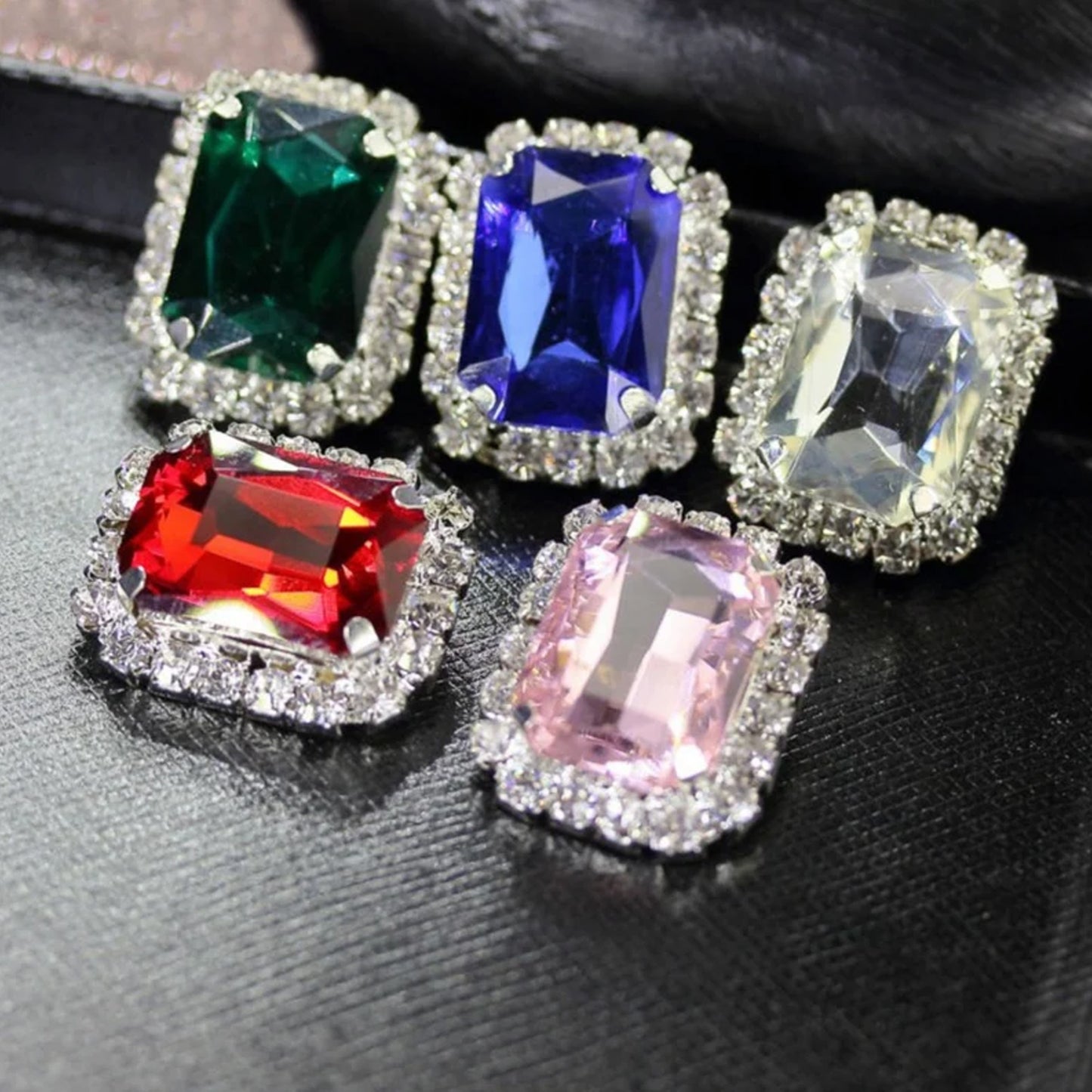 Colorful interchangeable diamond earrings featuring green, blue, red, clear, and pink gemstones