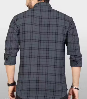 Person wearing a gray plaid shirt on a plain background