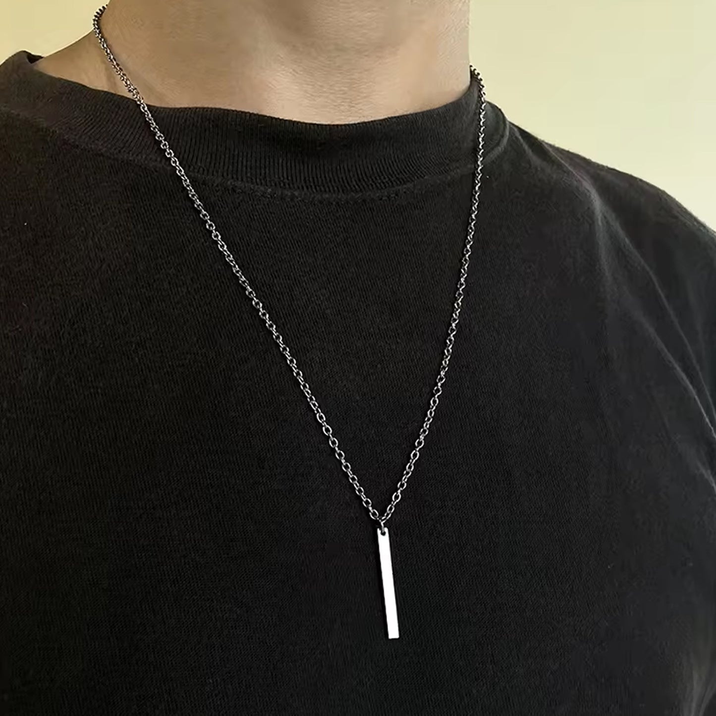Stainless steel locket necklace featuring a sleek design worn by a person in a black shirt