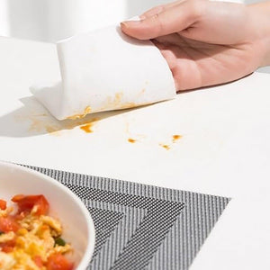 Hand using kitchen cleaning wipes to remove food stains from a tabletop surface