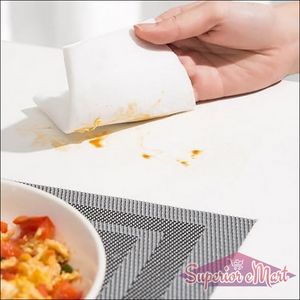 Hand using kitchen cleaning wipes to remove food stains from a tabletop surface