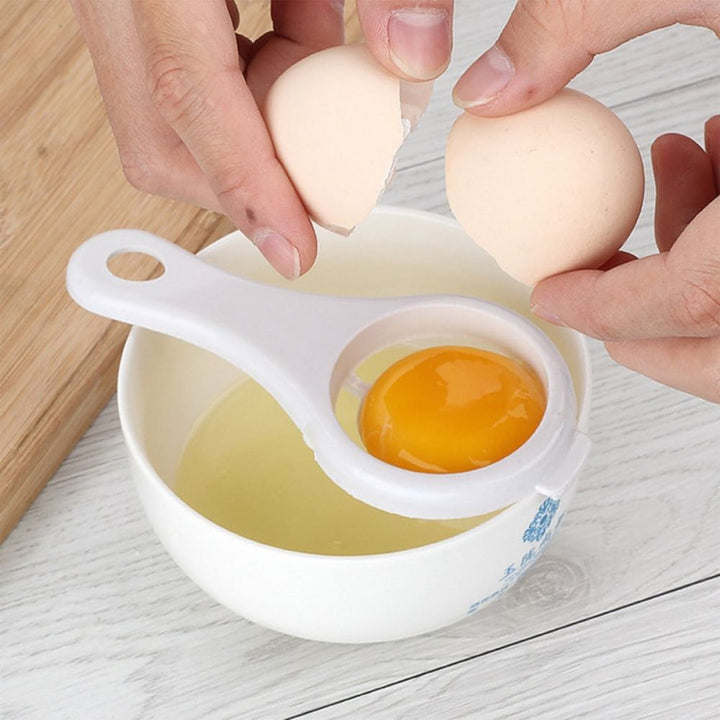 Hands using an egg yolk separator kitchen tool over a bowl to separate yolk from egg white