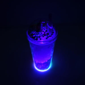 LED glow sipper bottle for kids illuminating with vibrant blue light in a dark setting