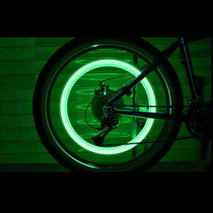 Green illuminated bike wheel featuring LED tire valve caps for enhanced visibility at night
