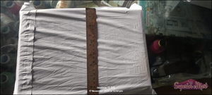 White poly mailer measured vertically with a wooden ruler to show height in inches and centimeters.