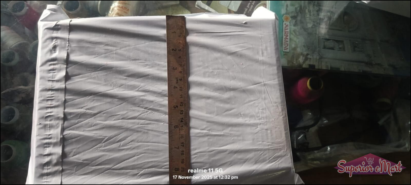 White poly mailer measured vertically with a wooden ruler to show height in inches and centimeters.