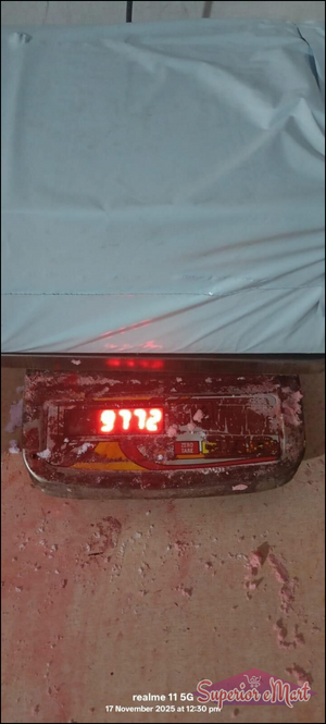 White poly mailer on a digital scale showing 9772 in red. Metal scale and floor with pink powder. Realme 11 5G watermark.