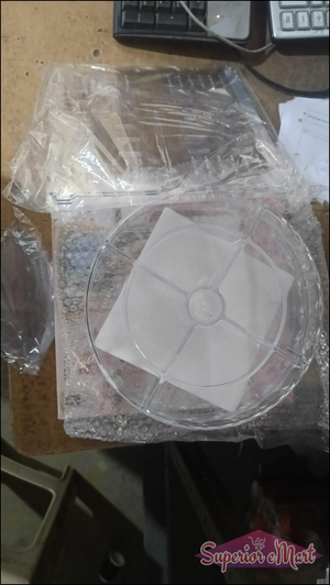 Clear plastic rotating organizer parts including a segmented base and flat tray, in protective bubble wrap packaging.