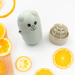 Cute green manual citrus juicer shaped like a bear with citrus slices on a wooden board