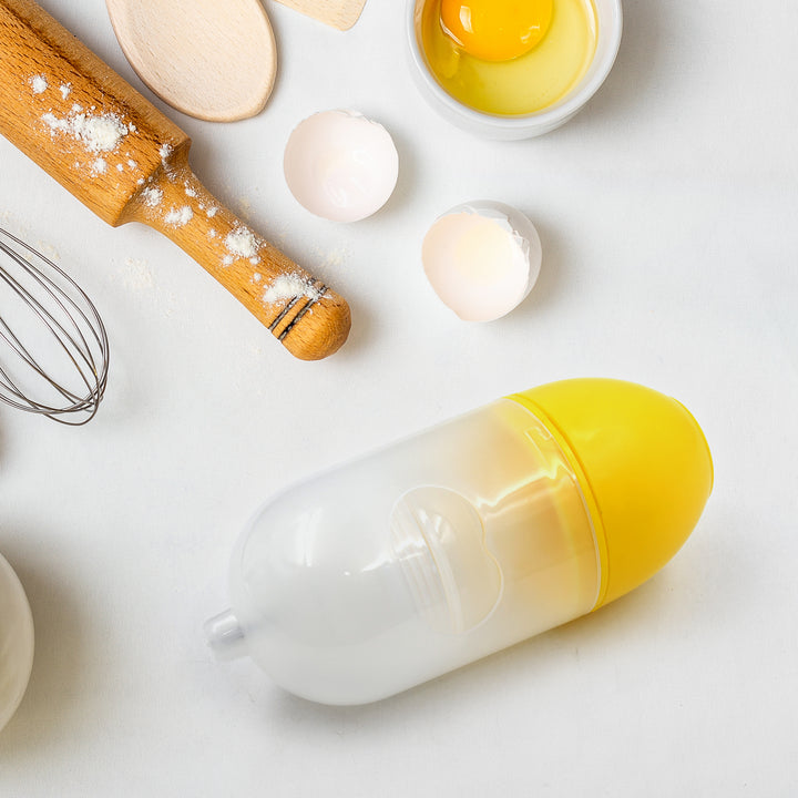 Manual egg scrambler with eggs, measuring spoons, and a whisk on a kitchen counter