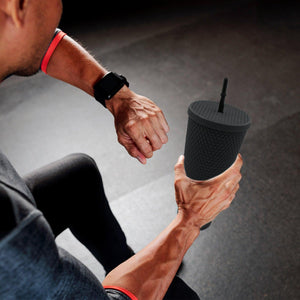 Matte studded tumbler with straw held by a person during a workout session for hydration