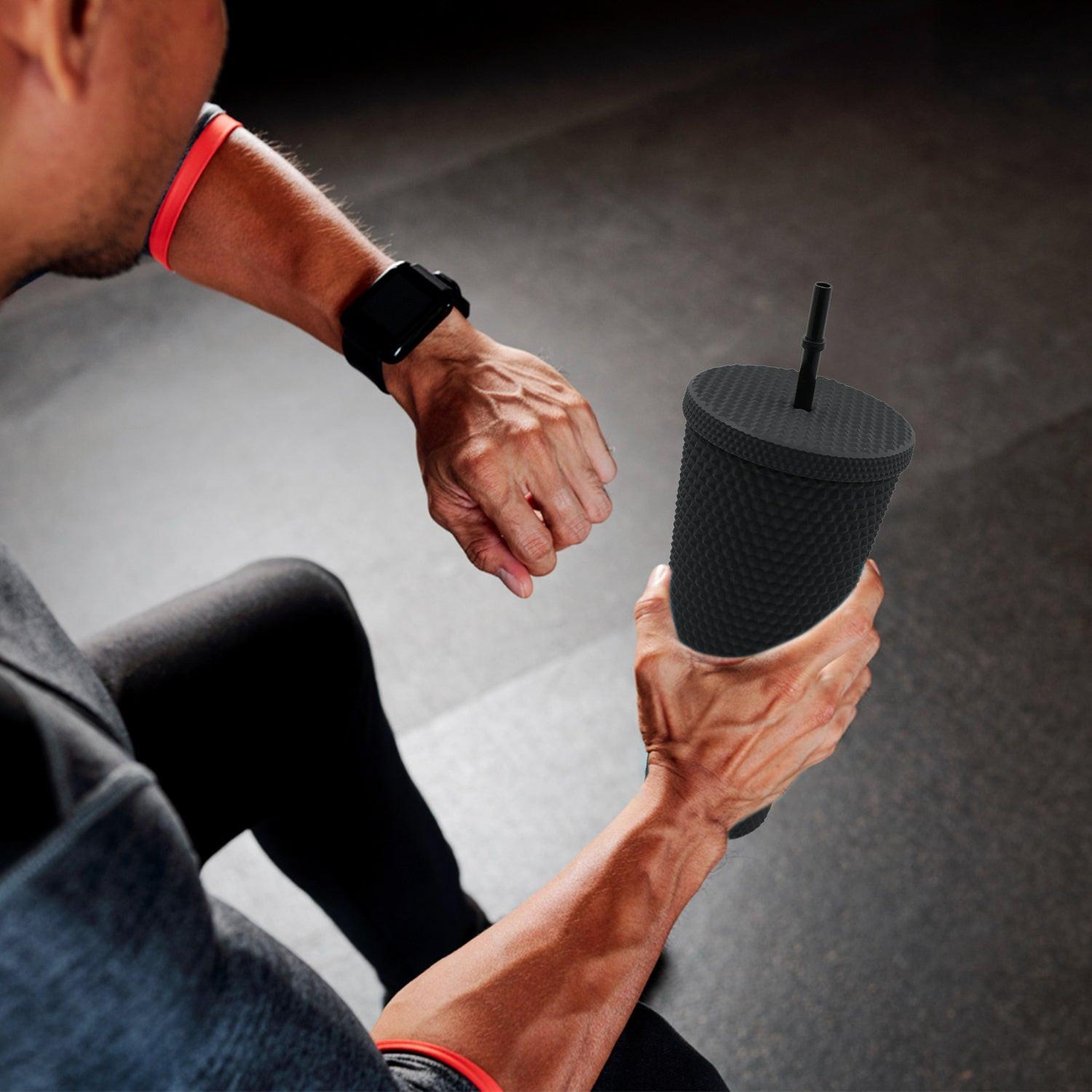 Matte studded tumbler with straw held by a person during a workout session for hydration