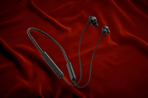 White wireless earbuds with a cable on a red fabric background