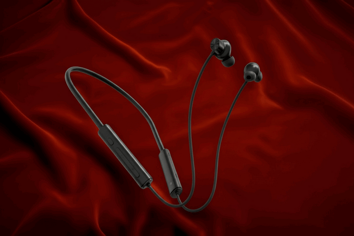 White wireless earbuds with a cable on a red fabric background