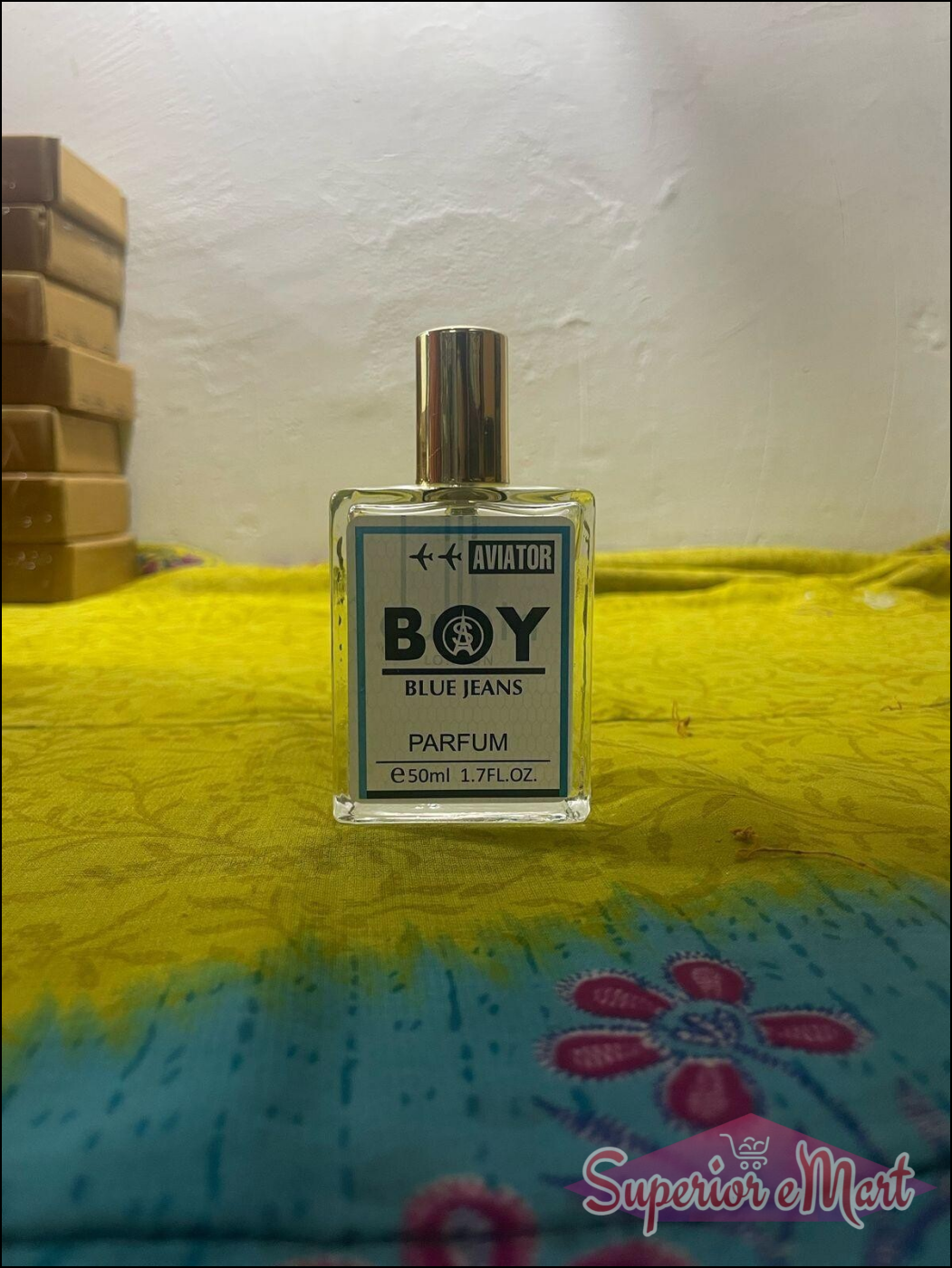 Aviator Boy Blue Jeans fragrance 50ml in clear bottle with gold cap on colorful fabric background