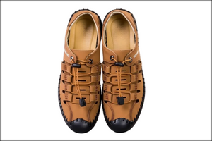 Pair of tan leather shoes with black soles on a gray background