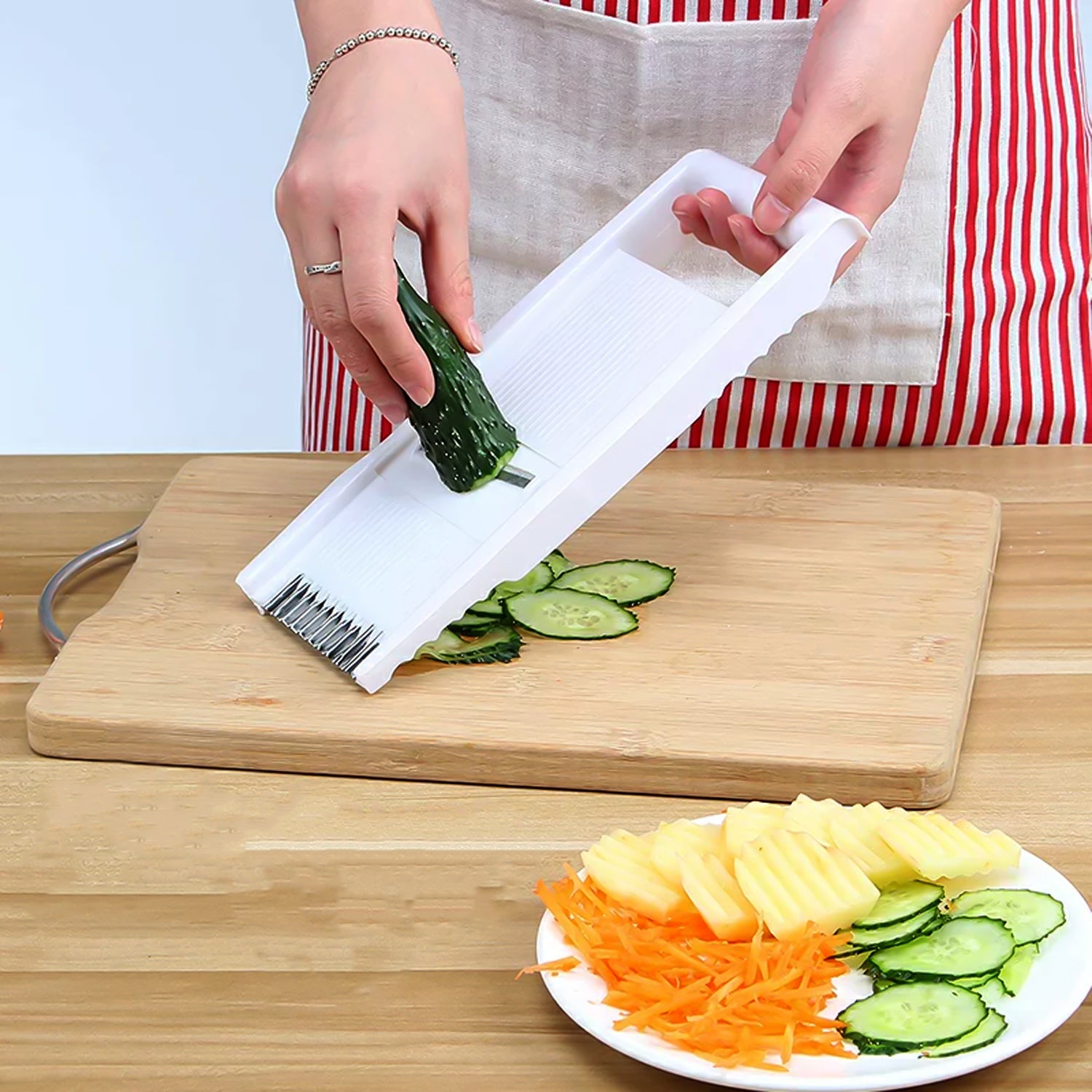 Superior eMart multi-functional slicer and peeler slicing cucumber on wooden board with prepared vegetables on plate