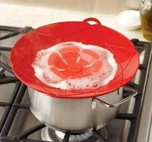 Red multifunctional silicone lid cover on a pot, preventing spills while cooking