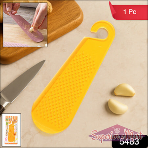 Yellow garlic and ginger grater tool on a countertop with garlic cloves and a knife