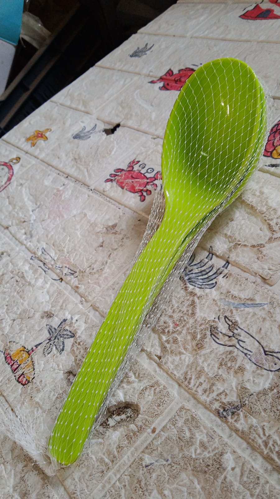 Bright green multipurpose kitchen ladle set on a textured surface, perfect for cooking and serving