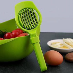 Green multipurpose slicer for fruits and eggs displayed beside fresh ingredients on a kitchen countertop