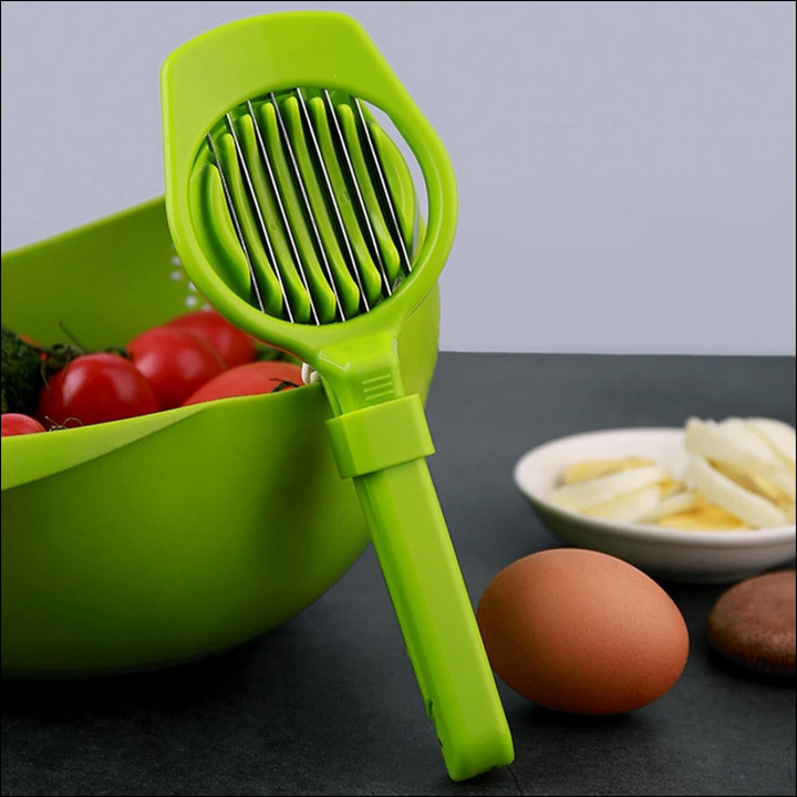 Green multipurpose slicer for fruits and eggs displayed beside fresh ingredients on a kitchen countertop