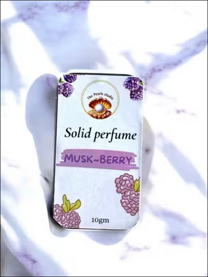 The Pearls Studio 10gm Musk-Berry solid perfume tin with berry illustrations, on a white marble background.