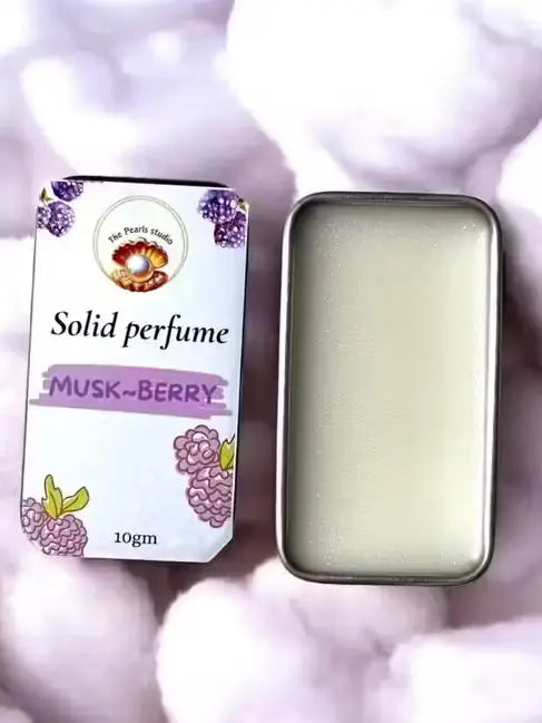 10g Musk-Berry solid perfume by The Pearls studio in a metal tin with white balm, on a soft white fluffy background.