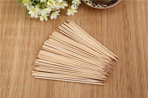 Pack of natural bamboo skewers on a wooden surface, ideal for grilling and cooking.
