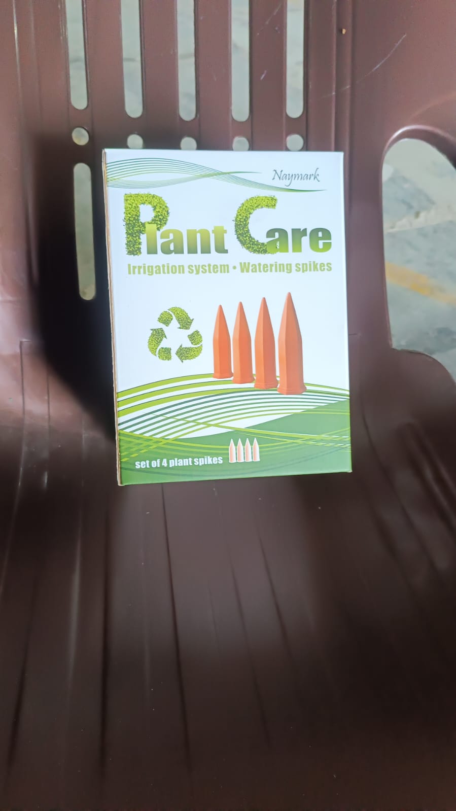 Set of 4 self watering spikes for plants arranged on a green and white packaging box