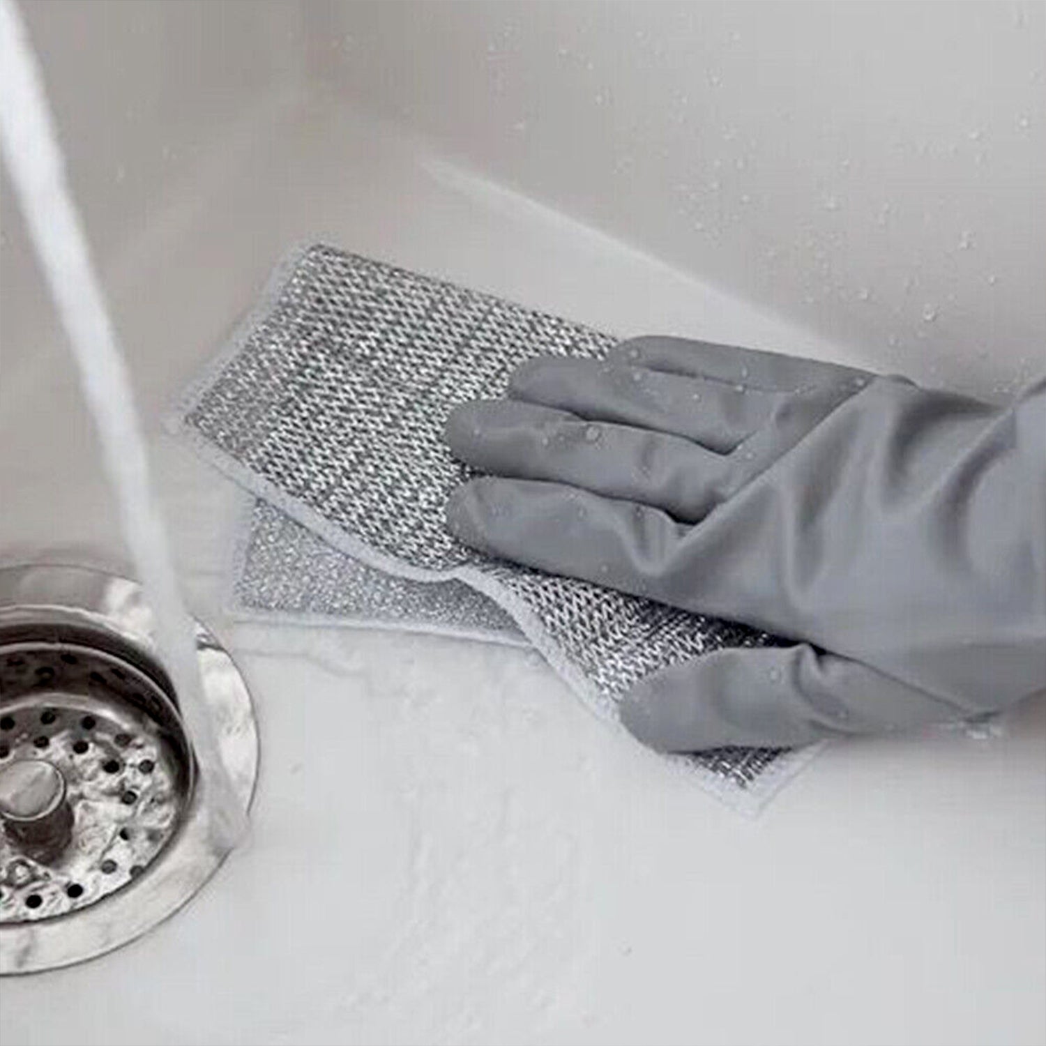 Non-scratch stainless steel scrubber being used on a sink with water running for effective cleaning