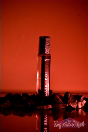 Nyro Dark Edge perfume in a sleek roll-on bottle surrounded by black stones