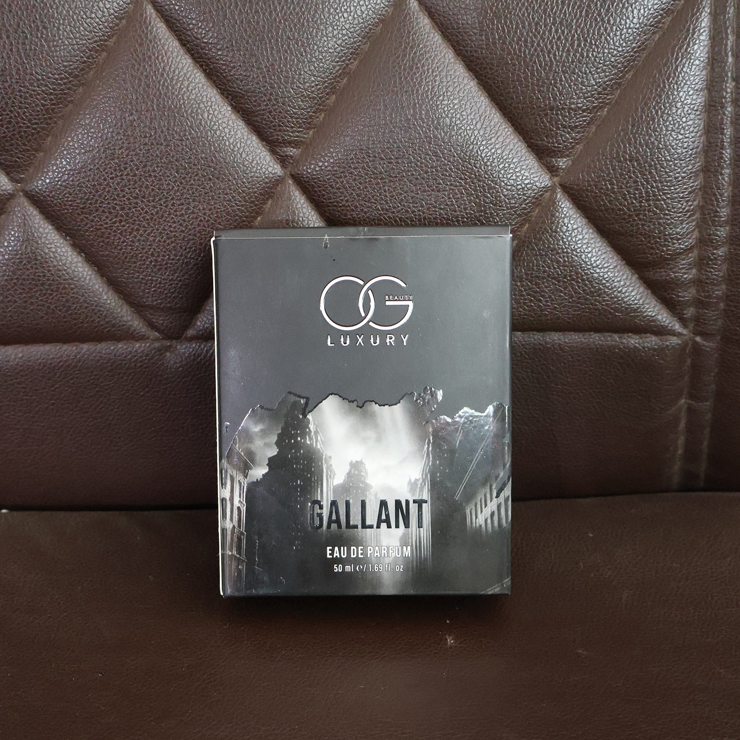 Og Beauty Gallant Eau De Parfum box displayed on a brown leather couch