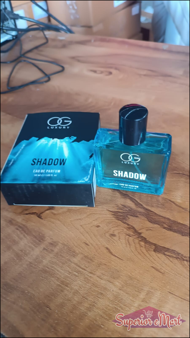 Og Beauty Luxury Shadow perfume in a blue bottle with a black box on a wooden surface