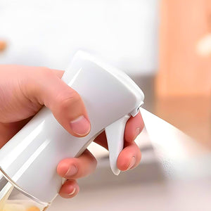 Hand holding a white oil spray bottle for cooking, perfect for even oil distribution on food