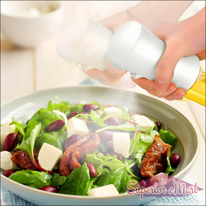 Oil spray bottle for cooking used to evenly mist fresh salad with olive oil and herbs