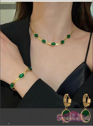 Gold jewelry set featuring dark green oval stones, including a necklace, bracelet, and matching hoop drop earrings.