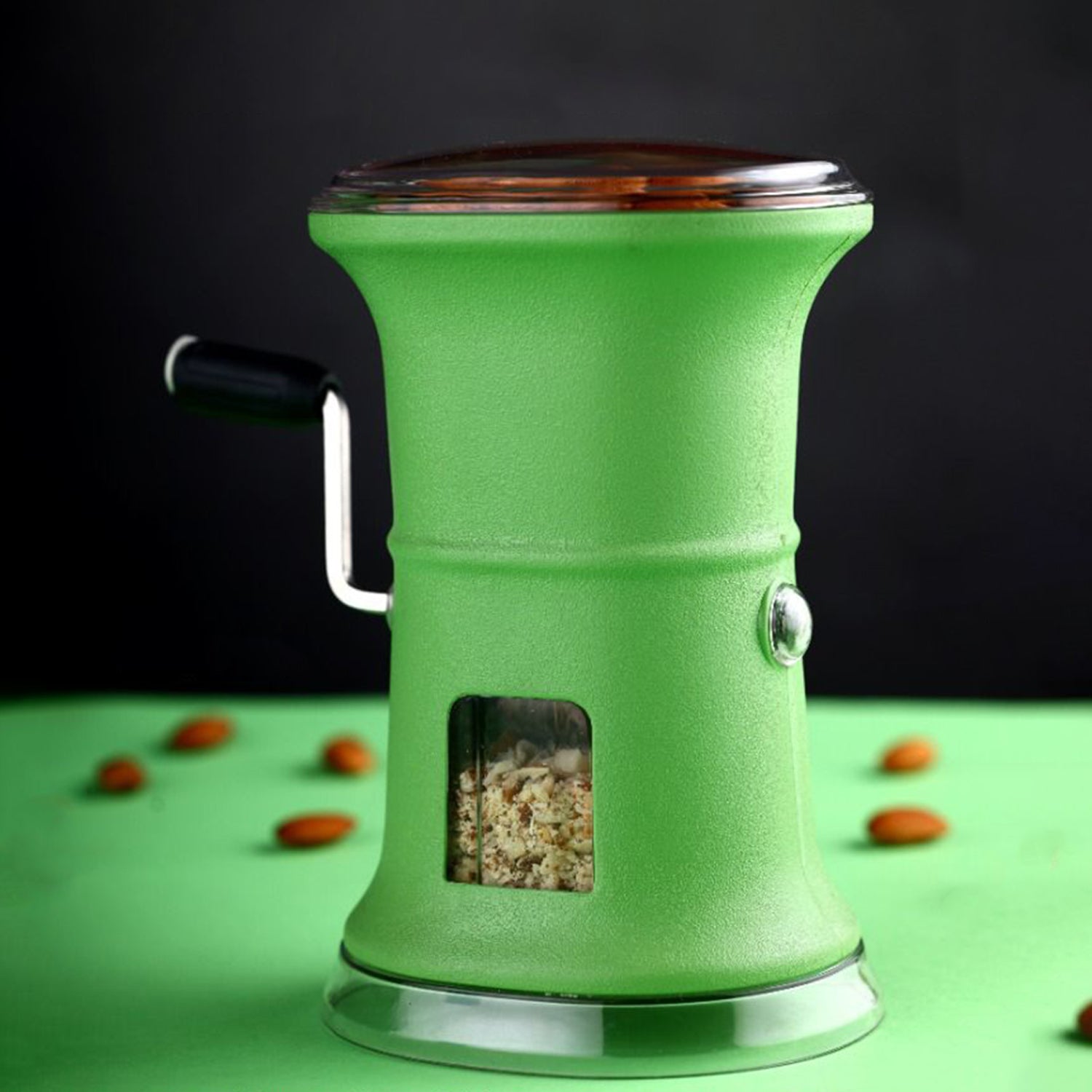 Green chilly and dry fruit hand grinder with crank handle and transparent window showing ground nuts inside