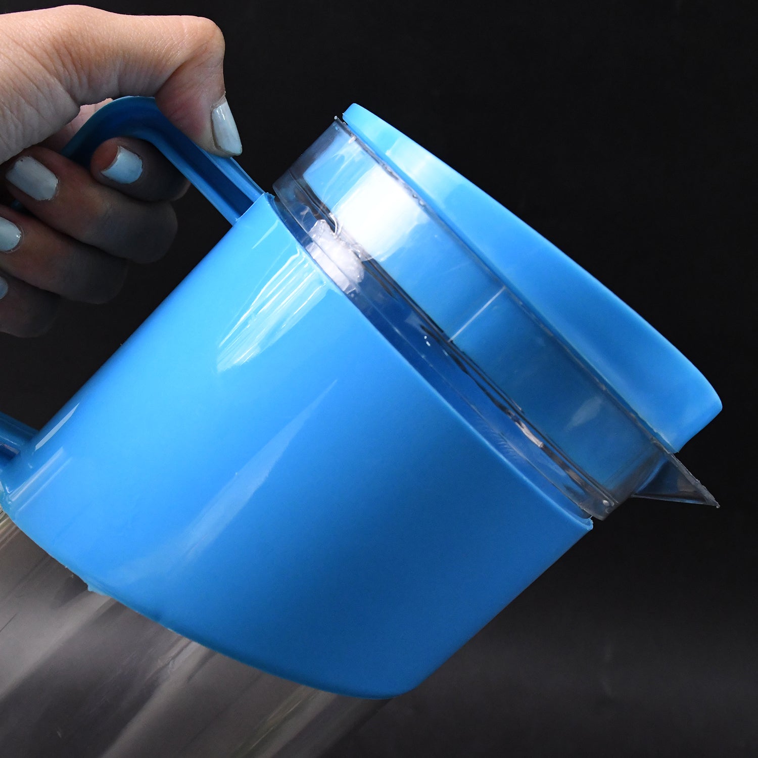 Blue Superior eMart 2000 ml water jug with glasses held by hand against black background