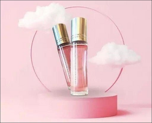 Two bottles of pink love perfume for women on a pastel pink background with fluffy clouds