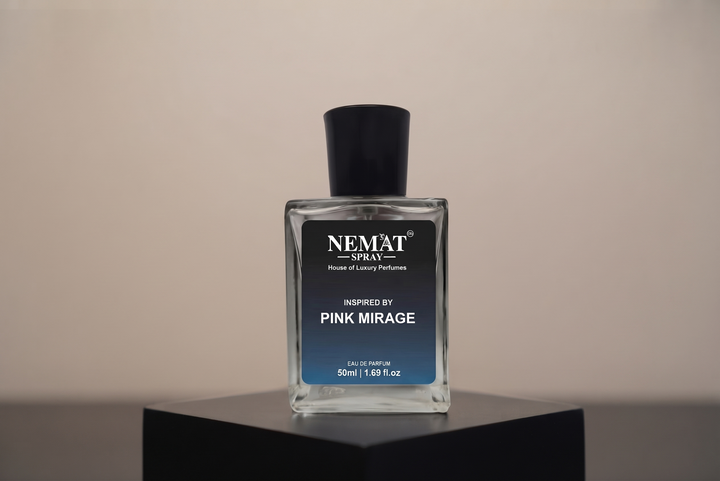 A rectangular glass perfume bottle with a black cap and a black-to-blue gradient label reading 'NEMAT SPRAY' and 'Inspired by Pink Mirage', displayed on a black pedestal against a warm beige background.
