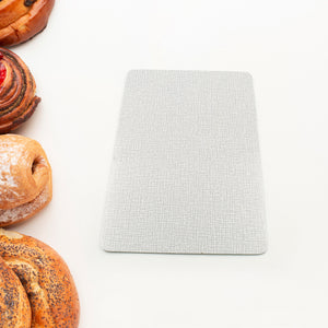 Durable plastic kitchen chopping board placed next to freshly baked pastries on a white background