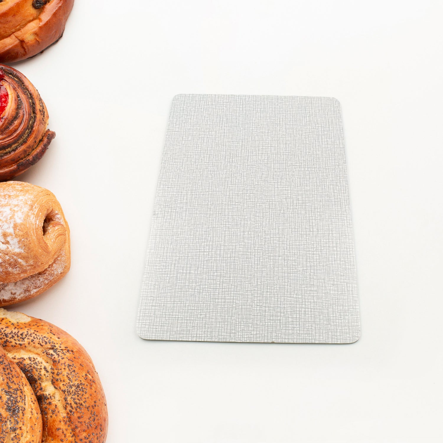 Durable plastic kitchen chopping board placed next to freshly baked pastries on a white background