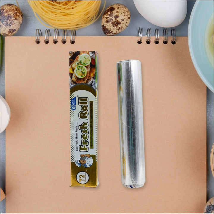 Heavy duty aluminum foil roll on a kitchen workspace with cooking ingredients and utensils